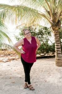 A traveler stands on the beach by a palm tree in Belize