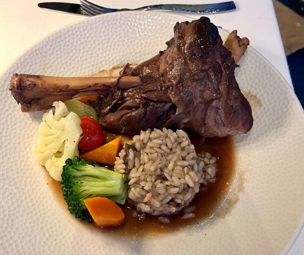 Braised ossobuco served with brown rice, mixed vegetables, and rich gravy on a white plate at Secrets Maroma Beach.